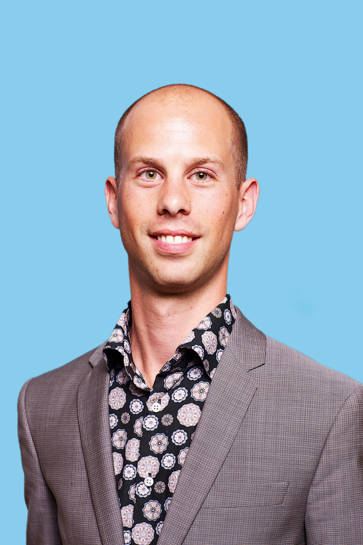 a balding man in a grey suit and flower shirt
