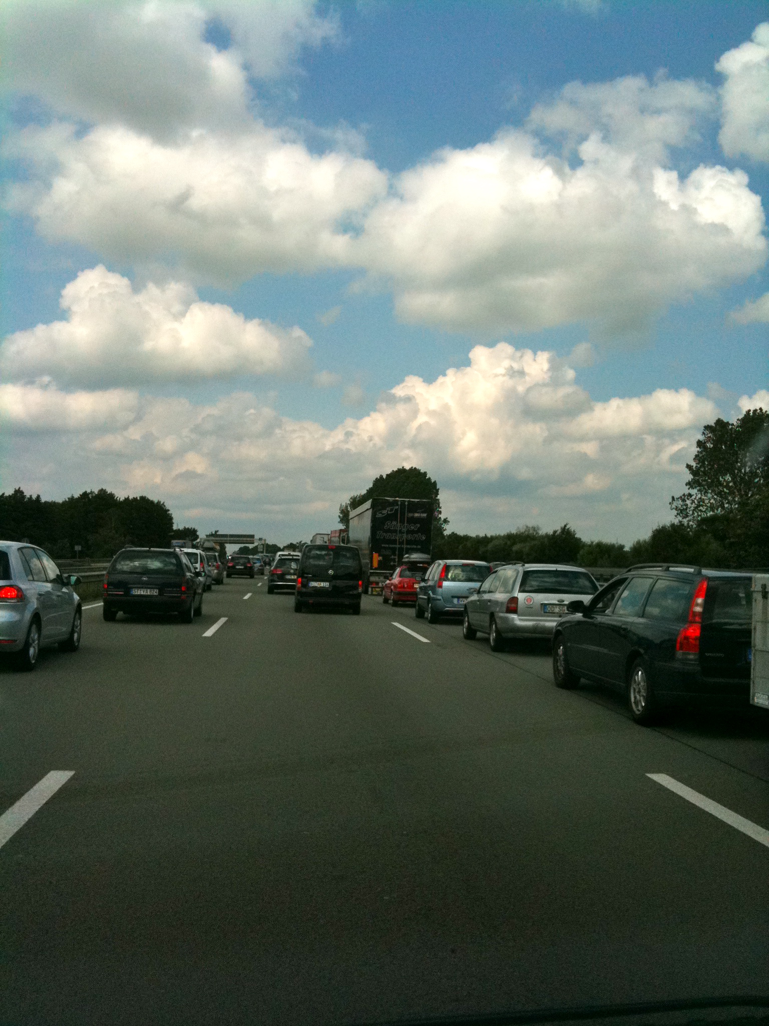 cars traveling down a road under lots of clouds