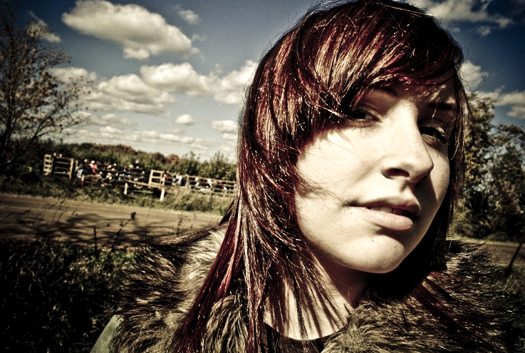 a woman with red hair stands in the grass