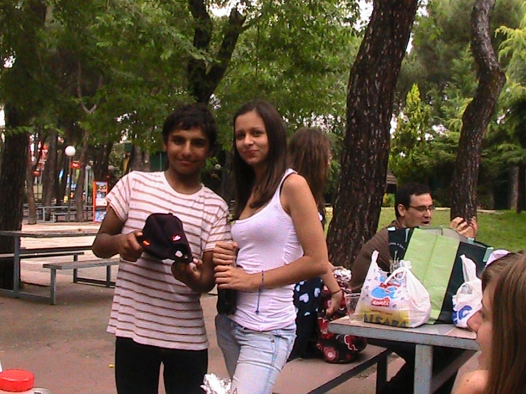 two young people stand in a park near picnic tables