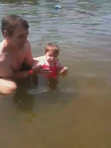 man and baby playing in the water at the beach