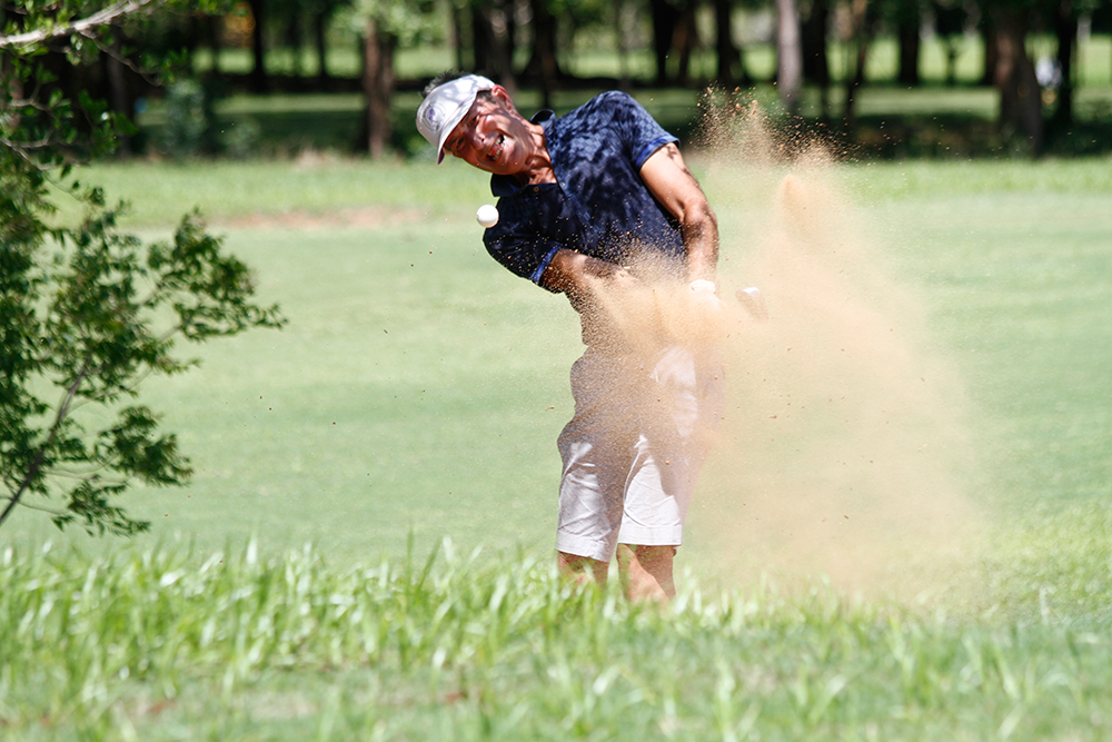 a man hitting a ball out of sand on a golf course