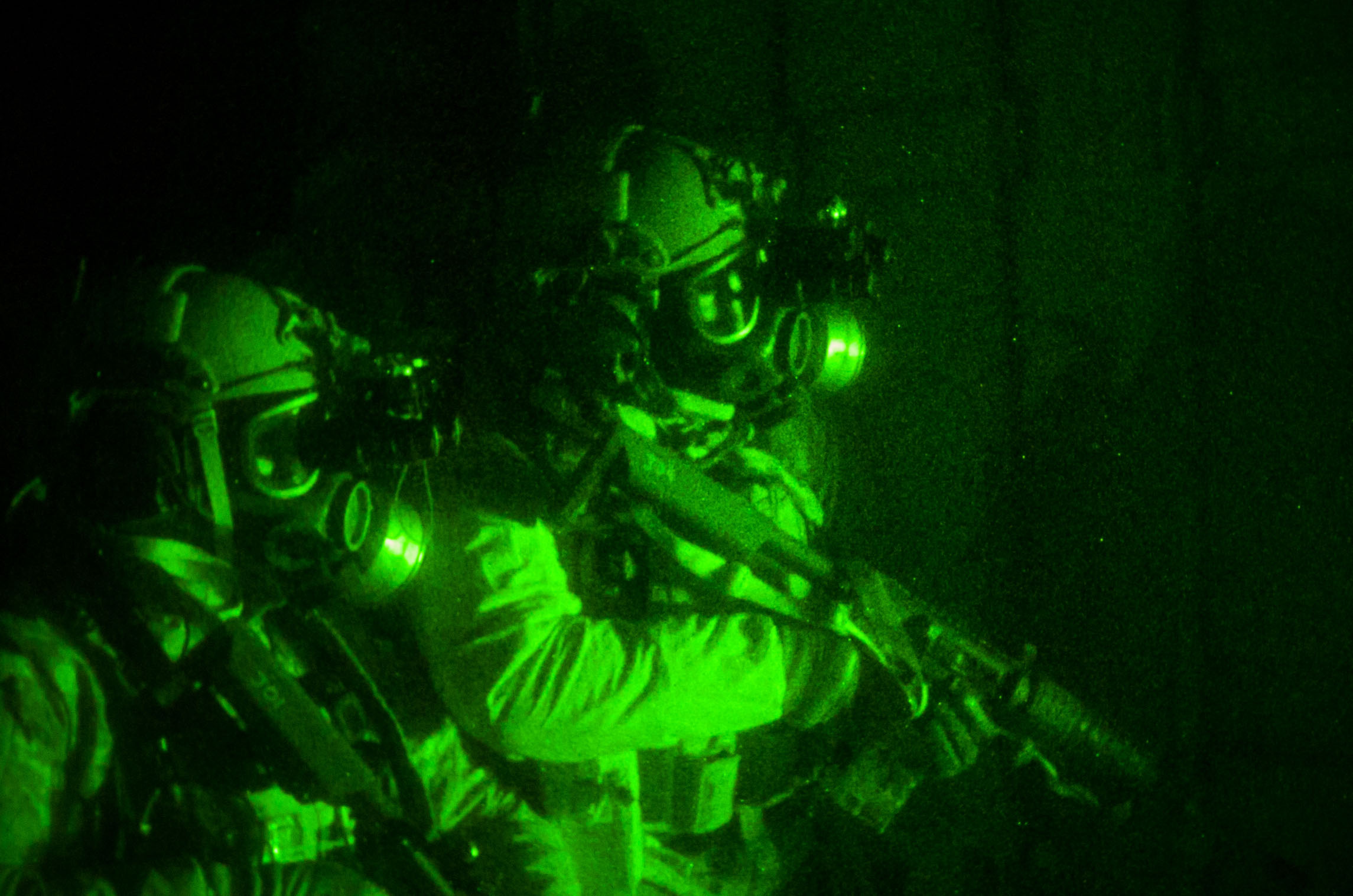 a man in the dark with his back lit by two men in camouflage gear