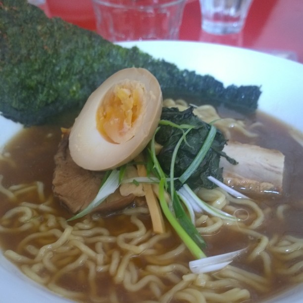 a bowl of noodles with chicken, egg, broccoli and sauce