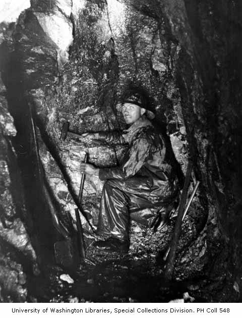 a man sitting in the hole of a tree on a trail