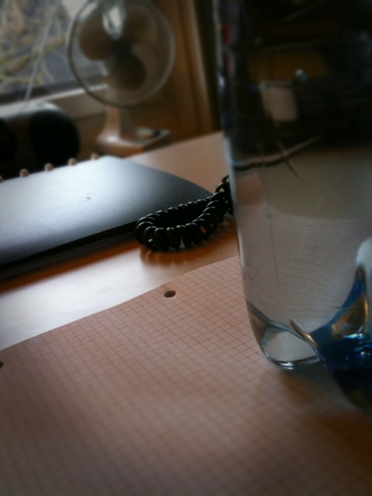 a glass of water sitting on top of a desk