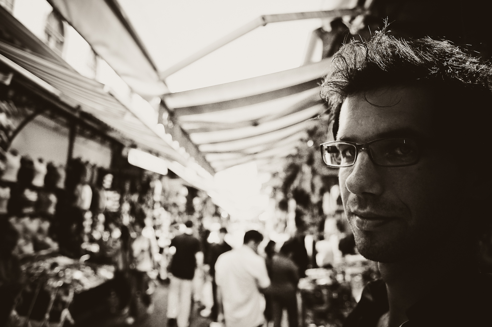 a man with glasses looking at people in the background