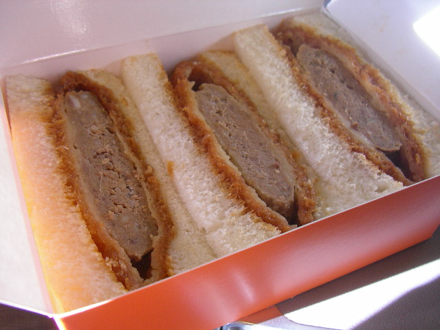 a sandwich in a paper container with a knife and fork