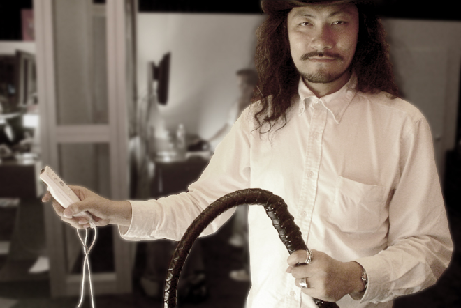 a man with long hair wearing a white shirt holding a whip