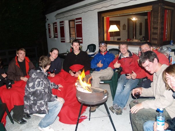 the group of people are gathered around a fire pit