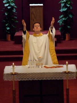 priest in front of a pew at the alter
