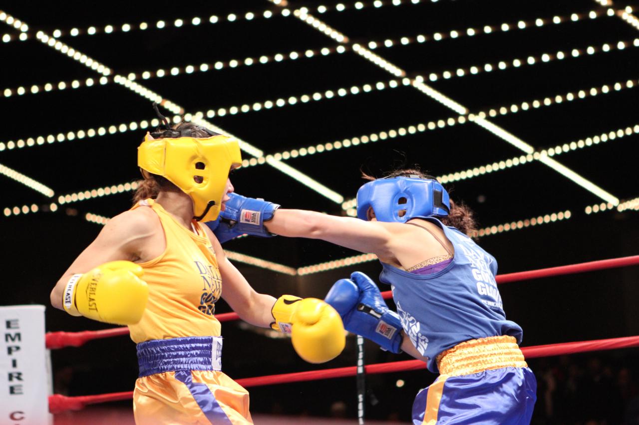 two fighters in blue and orange trunks are sparring