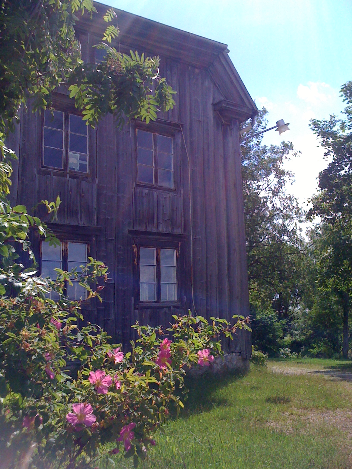 a wooden building sitting next to a lush green field