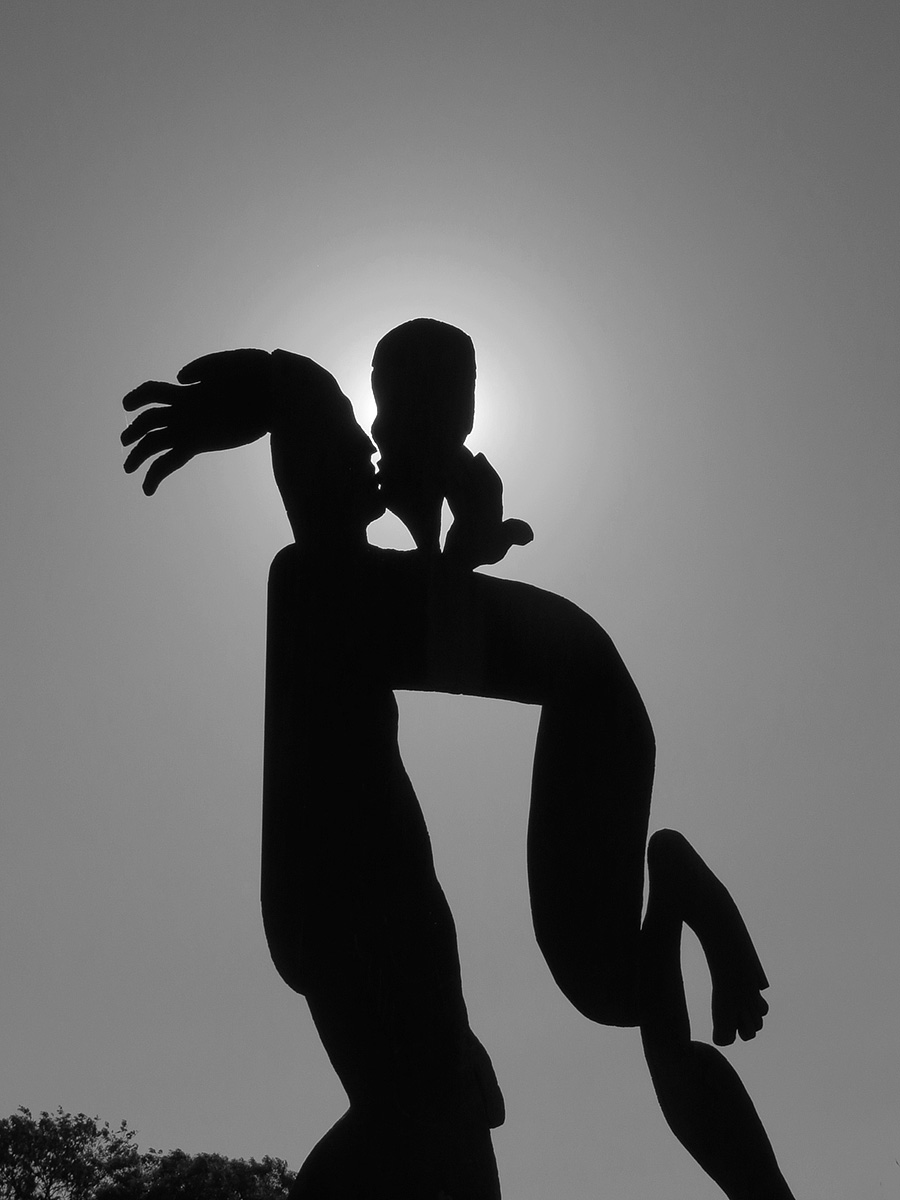 a sculpture is seen in silhouette with a sun light in the background