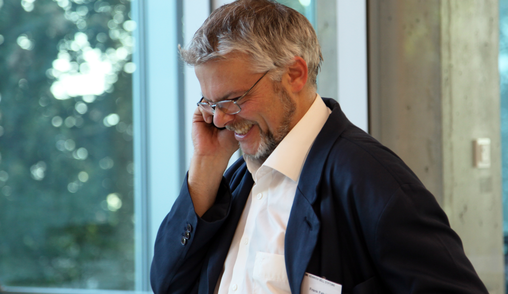 a man talking on a phone wearing a suit and glasses