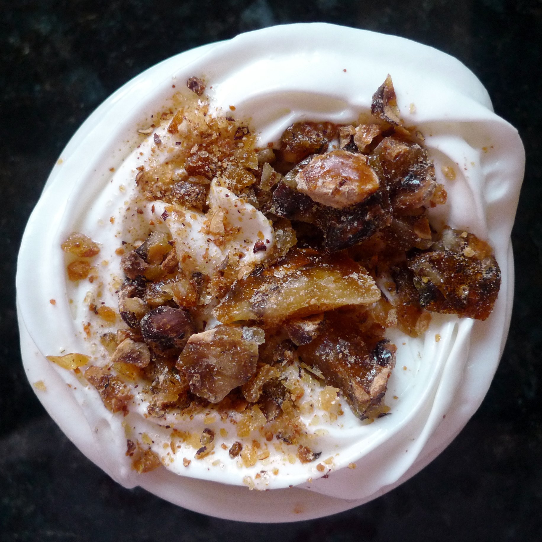 a dessert dish on a white plate that includes nuts and cream