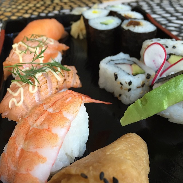 sushi on a black plate with a wooden spoon