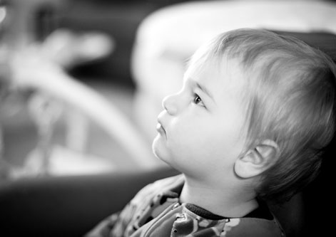 a small boy sitting in the backseat seat of a car looking to his left