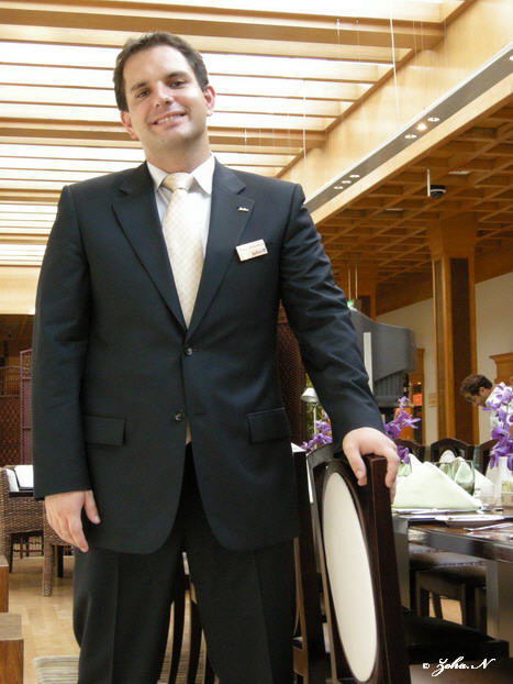 a man is standing with his hands in his pockets in front of a table