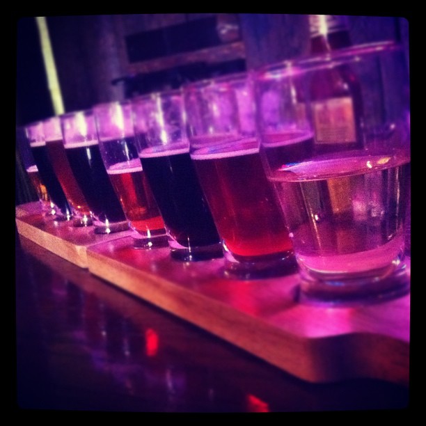 an array of glasses of different types and colors sitting on top of a wooden tray