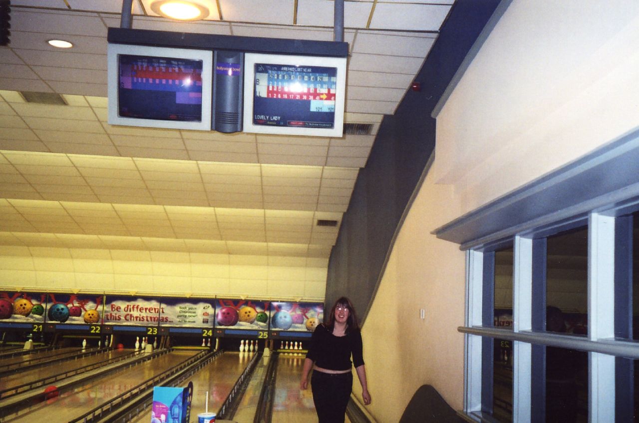 two people in black outfits standing by bowling pins