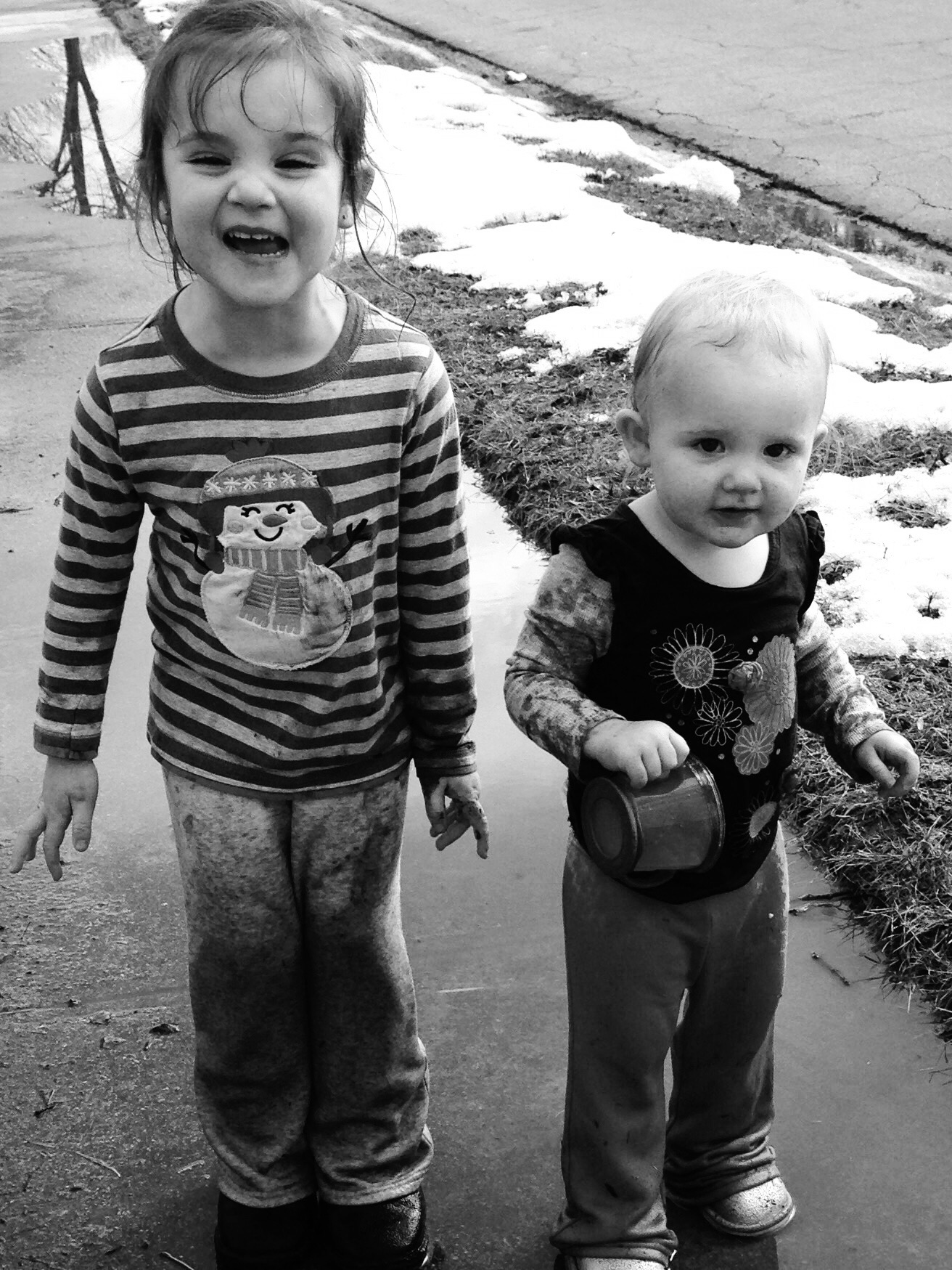 a boy and girl walking on a sidewalk in the snow