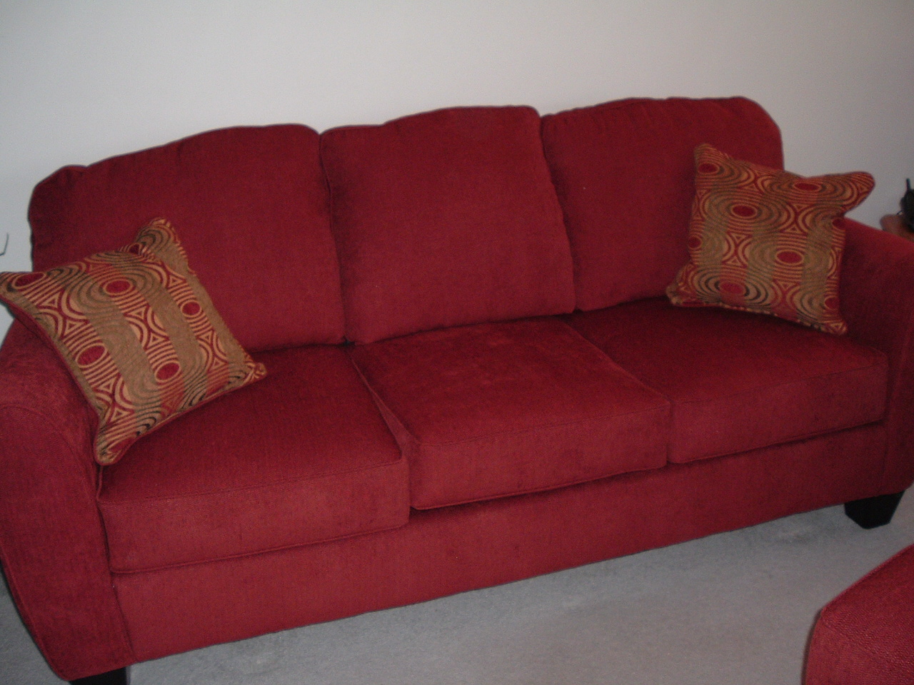 a red couch has brown and gold pillows