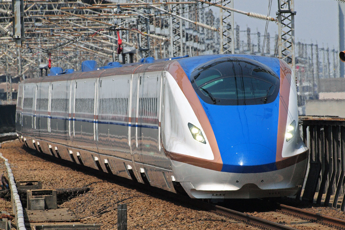 a white, blue, and silver train traveling down tracks