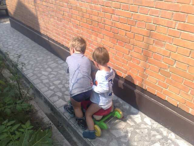 two children sit on the sidewalk on their toy