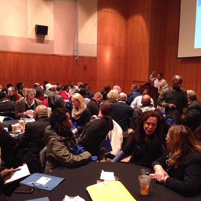 a group of people sitting around tables with notebooks