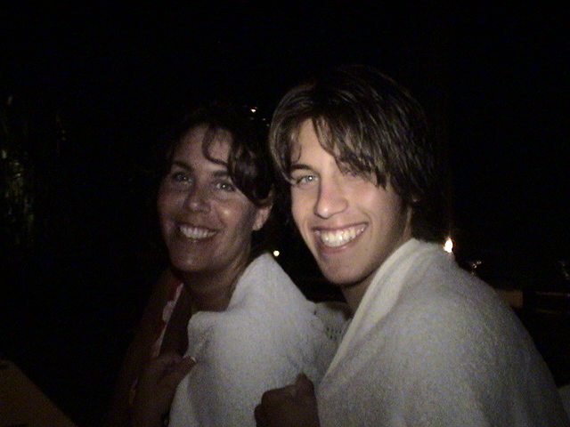 two young men smile at the camera at night