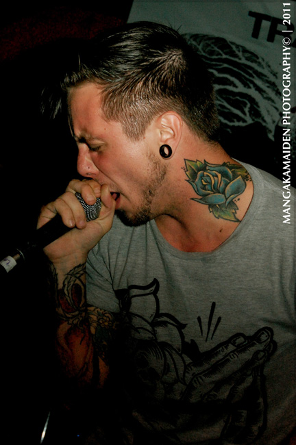 a tattooed man sings into a microphone