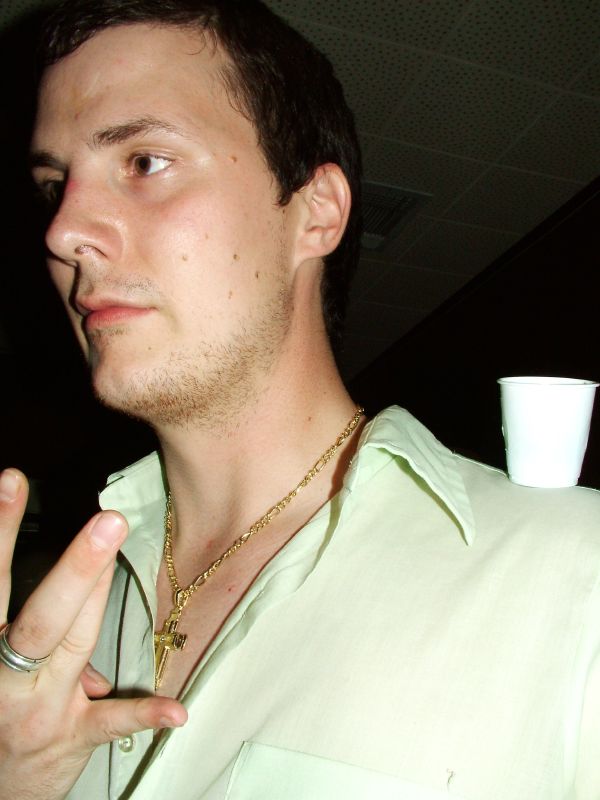 a man in white shirt holding a gold necklace on his chest