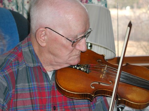 an old man in glasses playing on a violin