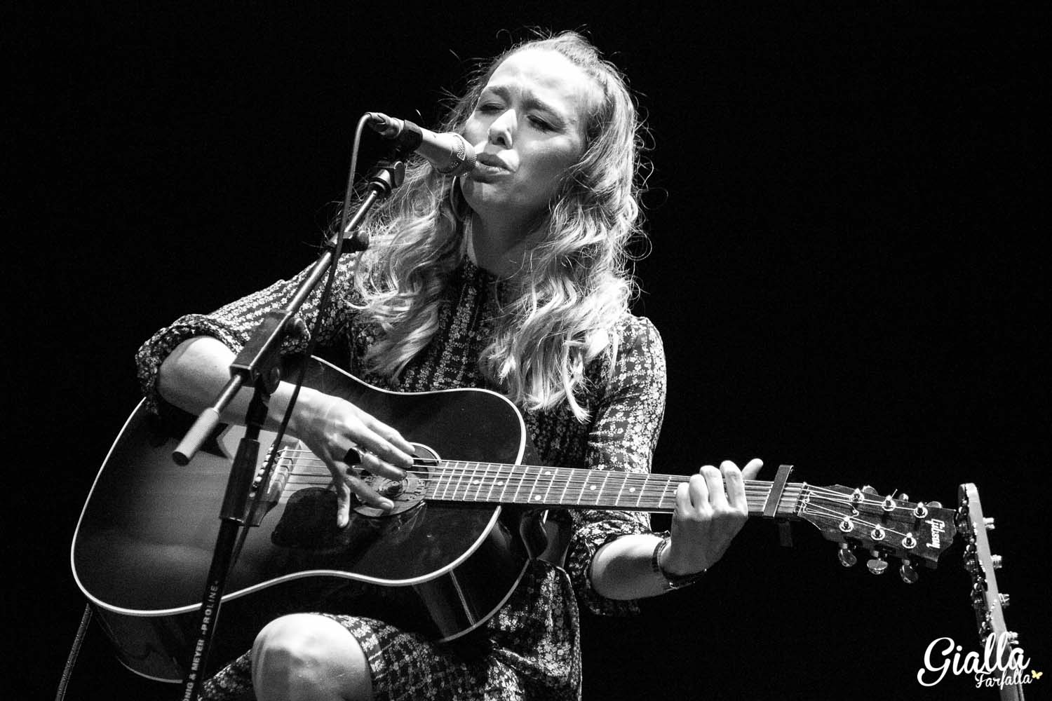 the musician is singing into a microphone while playing her guitar