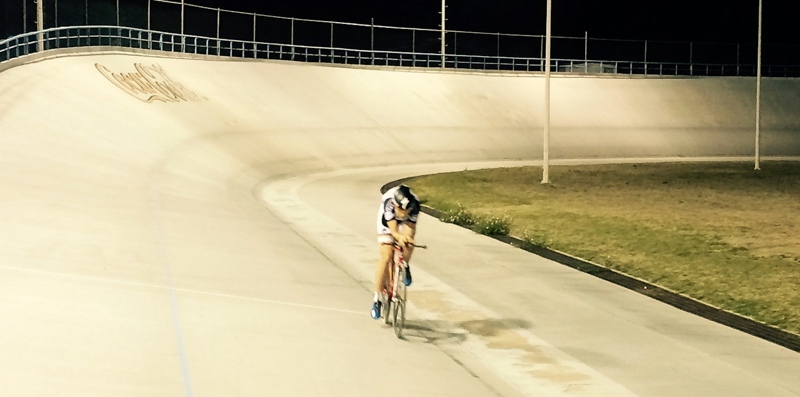 a man on a bicycle rides around an empty track at night
