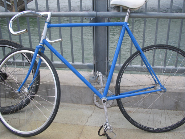 a close - up of a blue bike parked on a sidewalk near a river