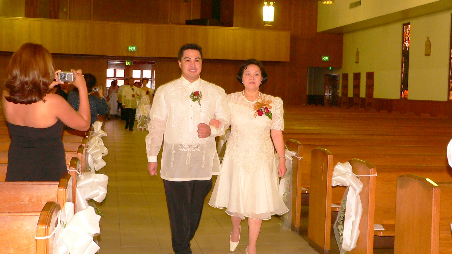 a couple dressed in traditional garb walk down the aisle