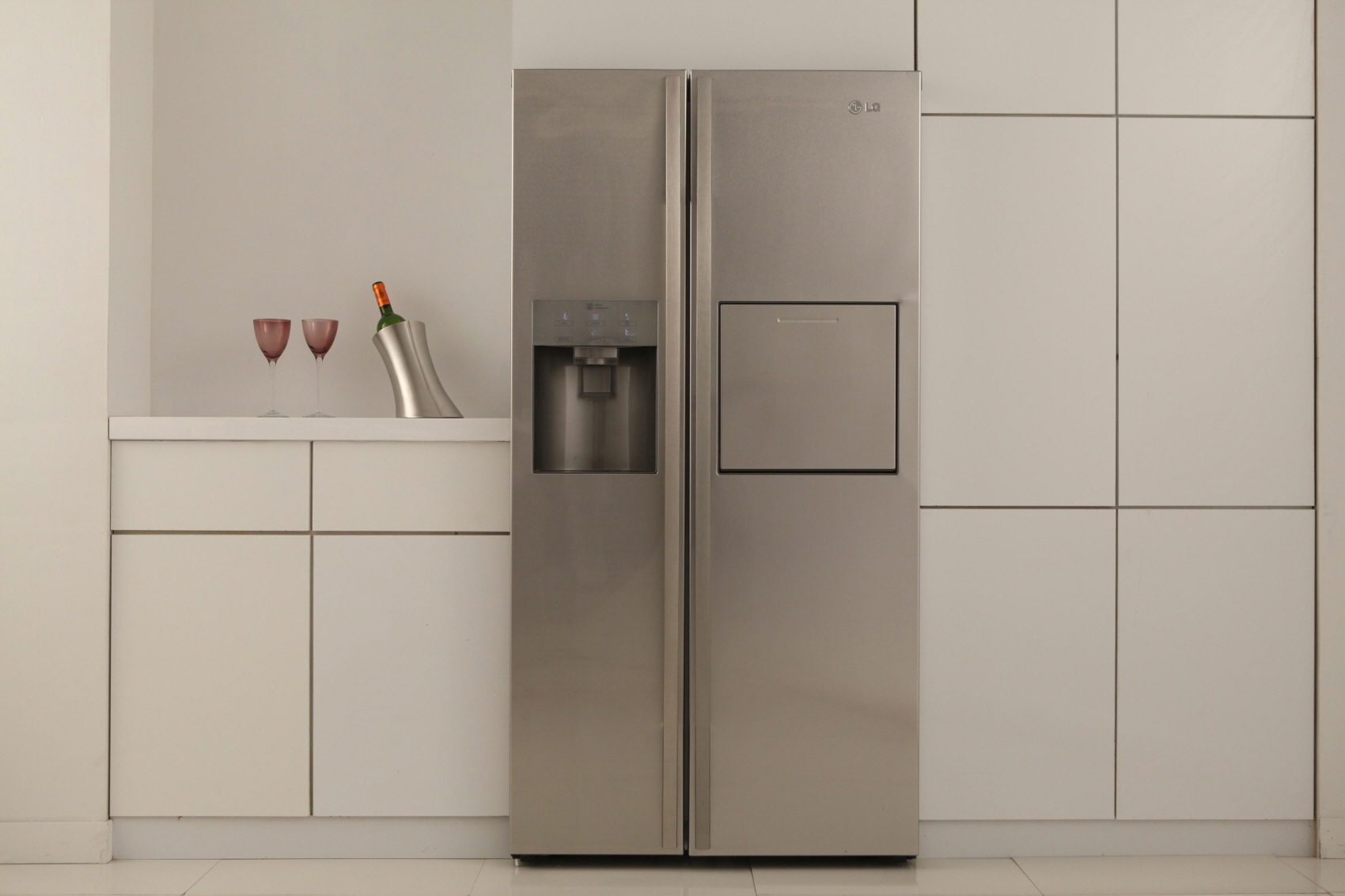 two wine glasses sit on the counter of a silver refrigerator