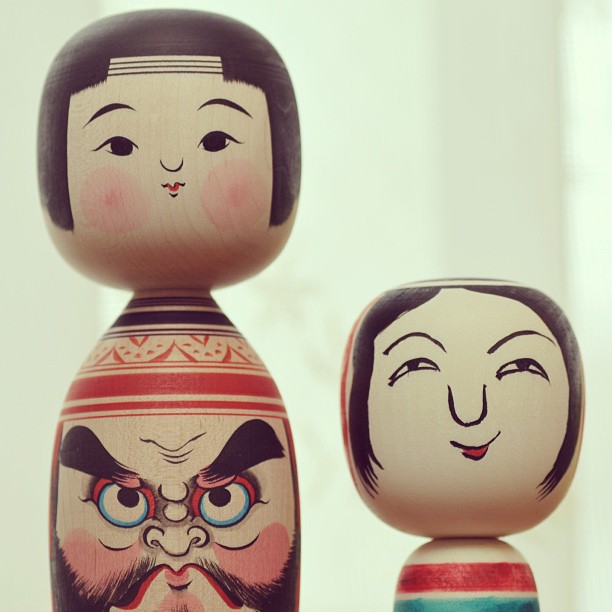 three wooden dolls have different designs on their faces