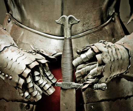 hands with gloves hold the sword on a medieval - styled background