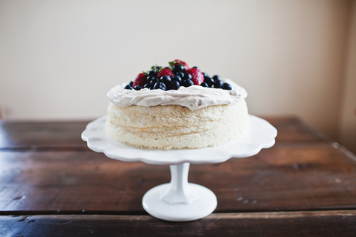 a single layer cake on a stand with berries