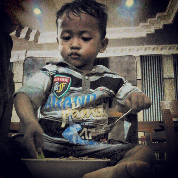 a little boy sits on a chair eating food