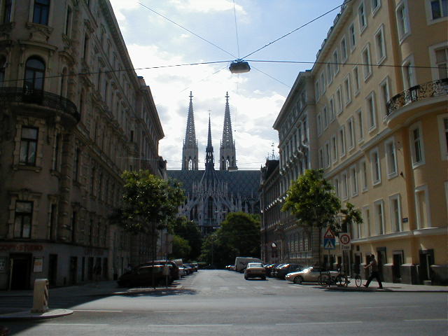 the cathedral is next to a large church and many people are walking on a street