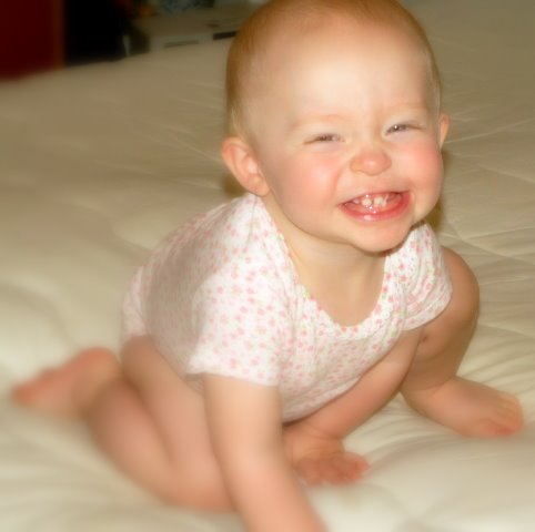 a baby girl smiling while laying on the bed