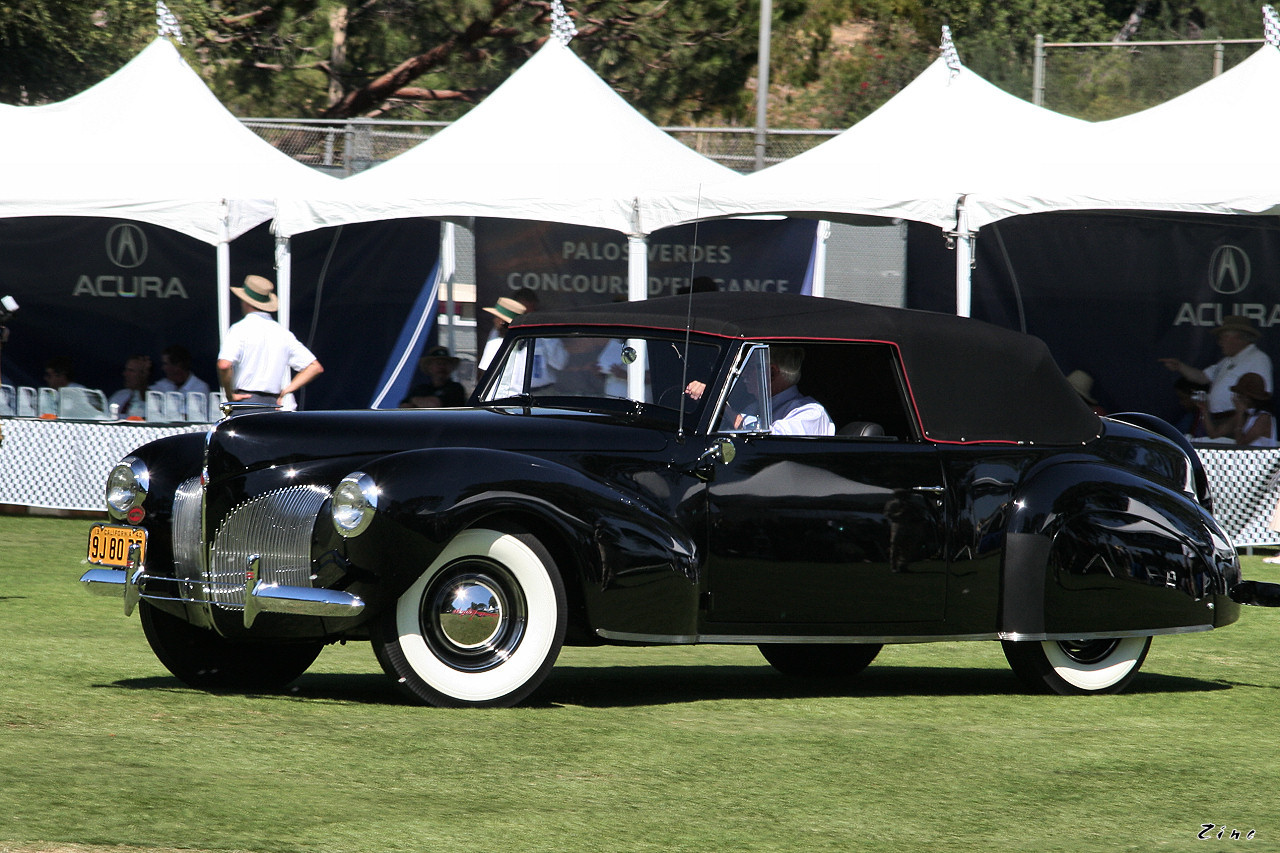 an old model car in the grass near tents