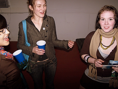 three s smile as one holds a paper cup and laughs