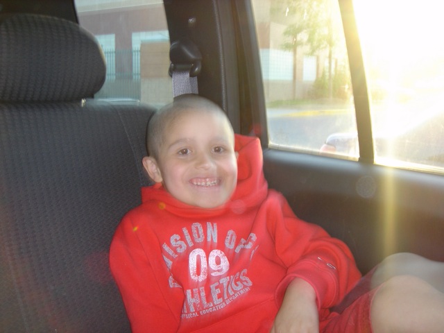 a child in a red shirt in the back seat of a car