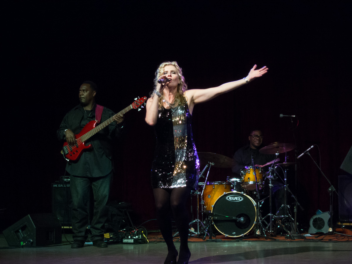 woman wearing black and shiny dress performing on stage