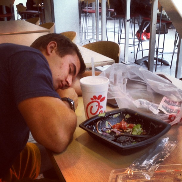 the young man is asleep on the table beside his food
